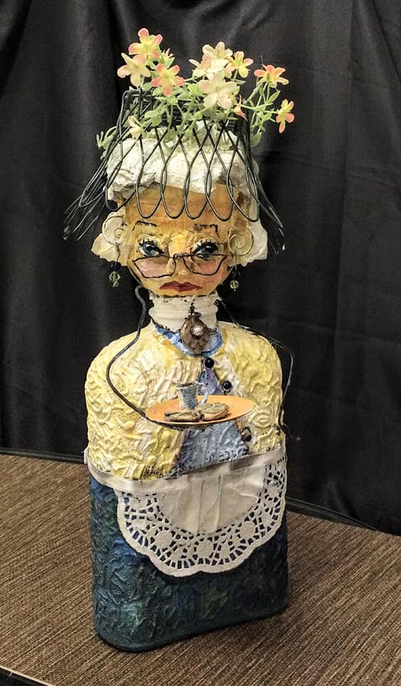 ecccentric woman, wire hat with flowers blue bottle for body, wire frame glasses